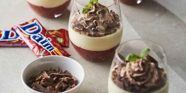 Dessertglas i lager med chokladmousse, grädde och jordgubbspuré, garnerade med mynta. Dime-kakor och chokladspån intill.